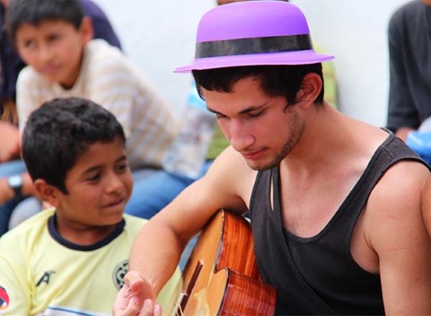 A teen plays the guitar for kids at a youth event in Mexico