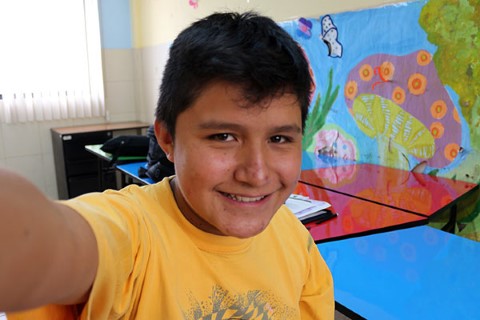 Jaime in a yellow T-shirt takes a selfie.