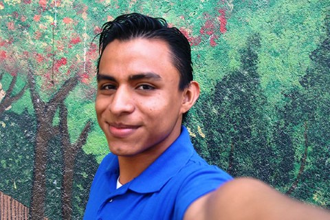 Marlon takes a selfie in front of a colorful mural.