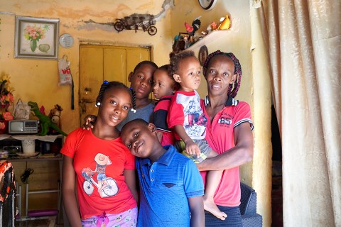 a family of six hugging inside their home