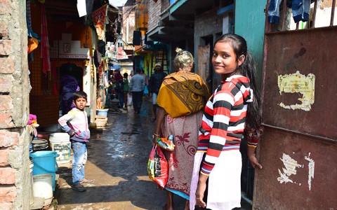 a young girl is standing in a narrow alleyway