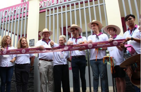 a group of people cutting a ribbon in front of a building